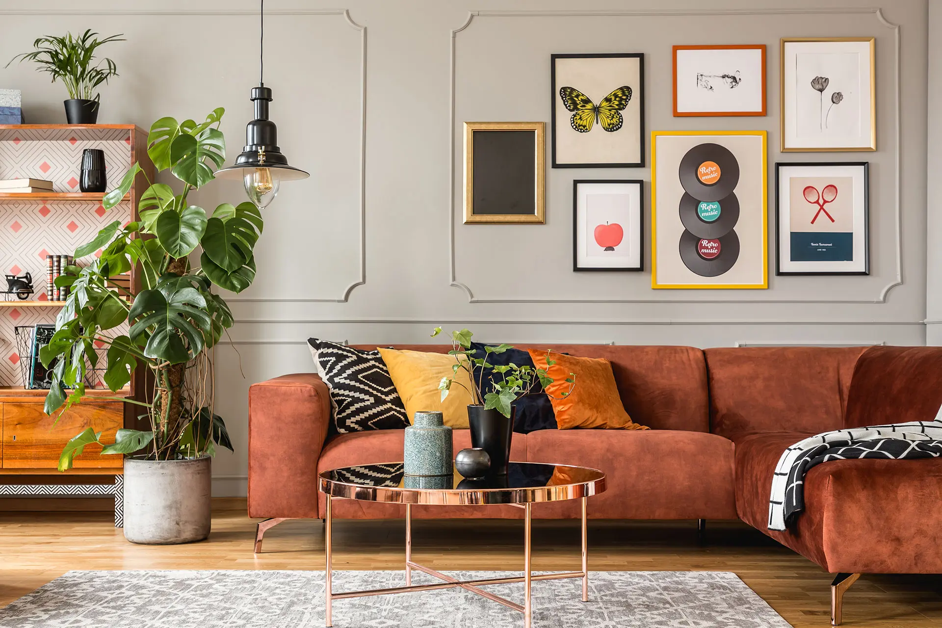 Modern living room with rust velvet sofa, gallery wall art, and copper coffee table