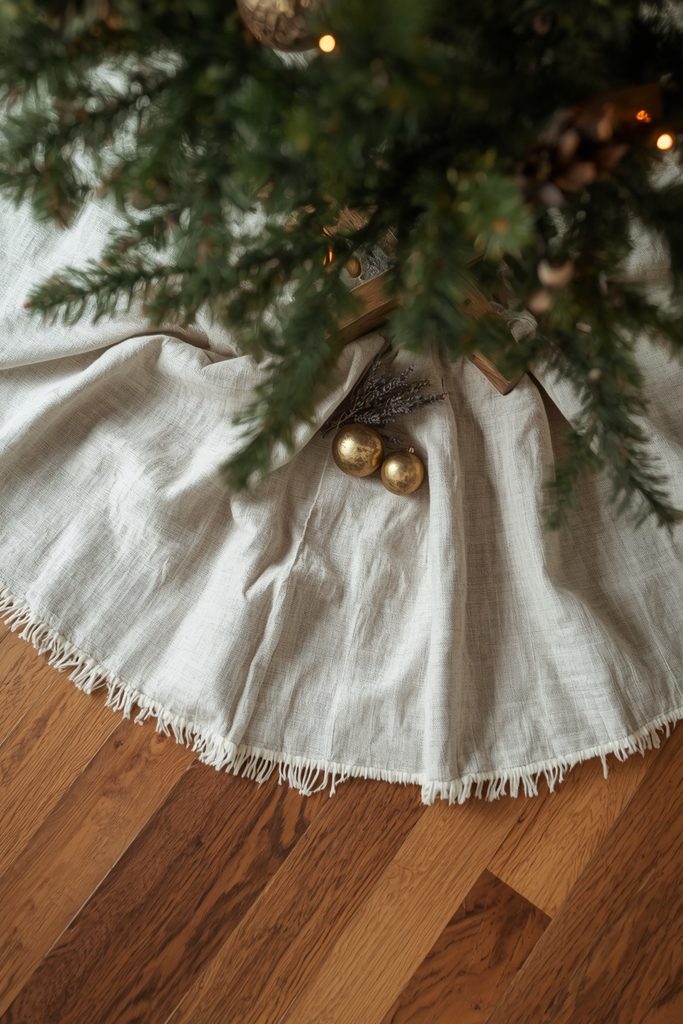 Raw-edged linen tree skirt with brass accents beneath a Christmas tree as rustic Christmas home decor