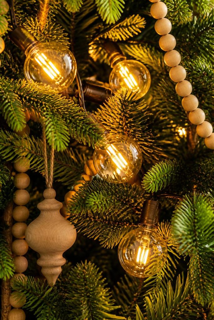 Glowing G40 globe bulbs nestled deep in fir branches for warm rustic Christmas home decor