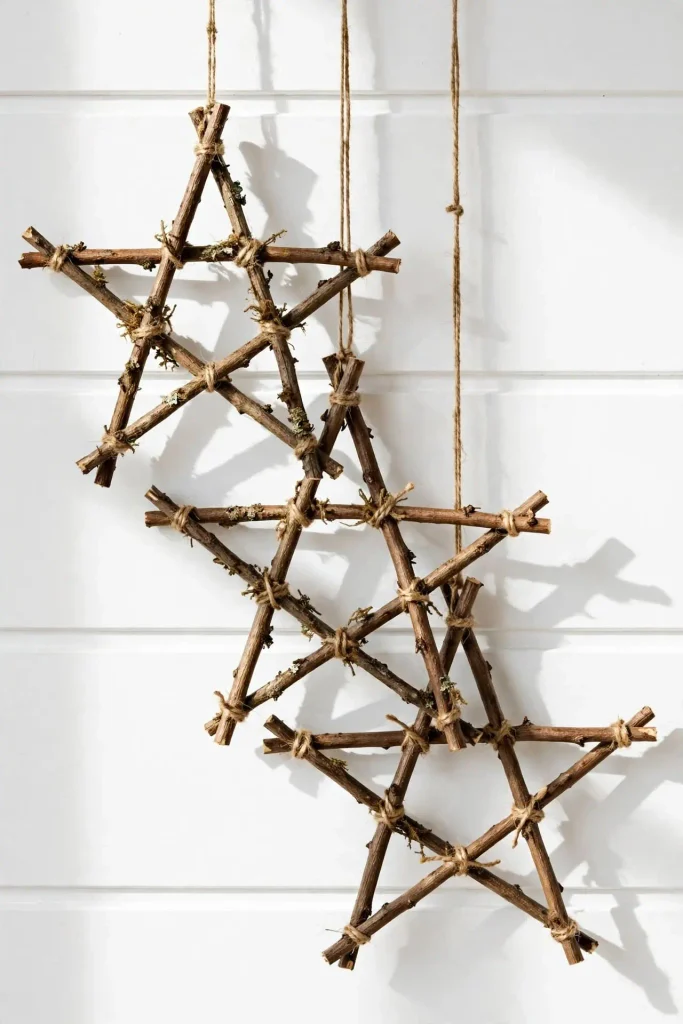 Three handmade rustic twig stars tied with twine hanging on white shiplap for diy Christmas home decor.